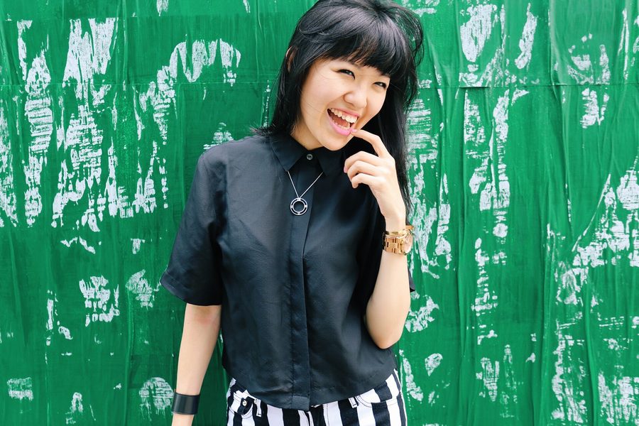 Laughing woman in black against a green wall — candid NYC street style