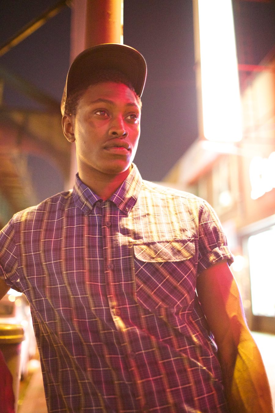 Young man under neon lights at night — moody New York street portrait