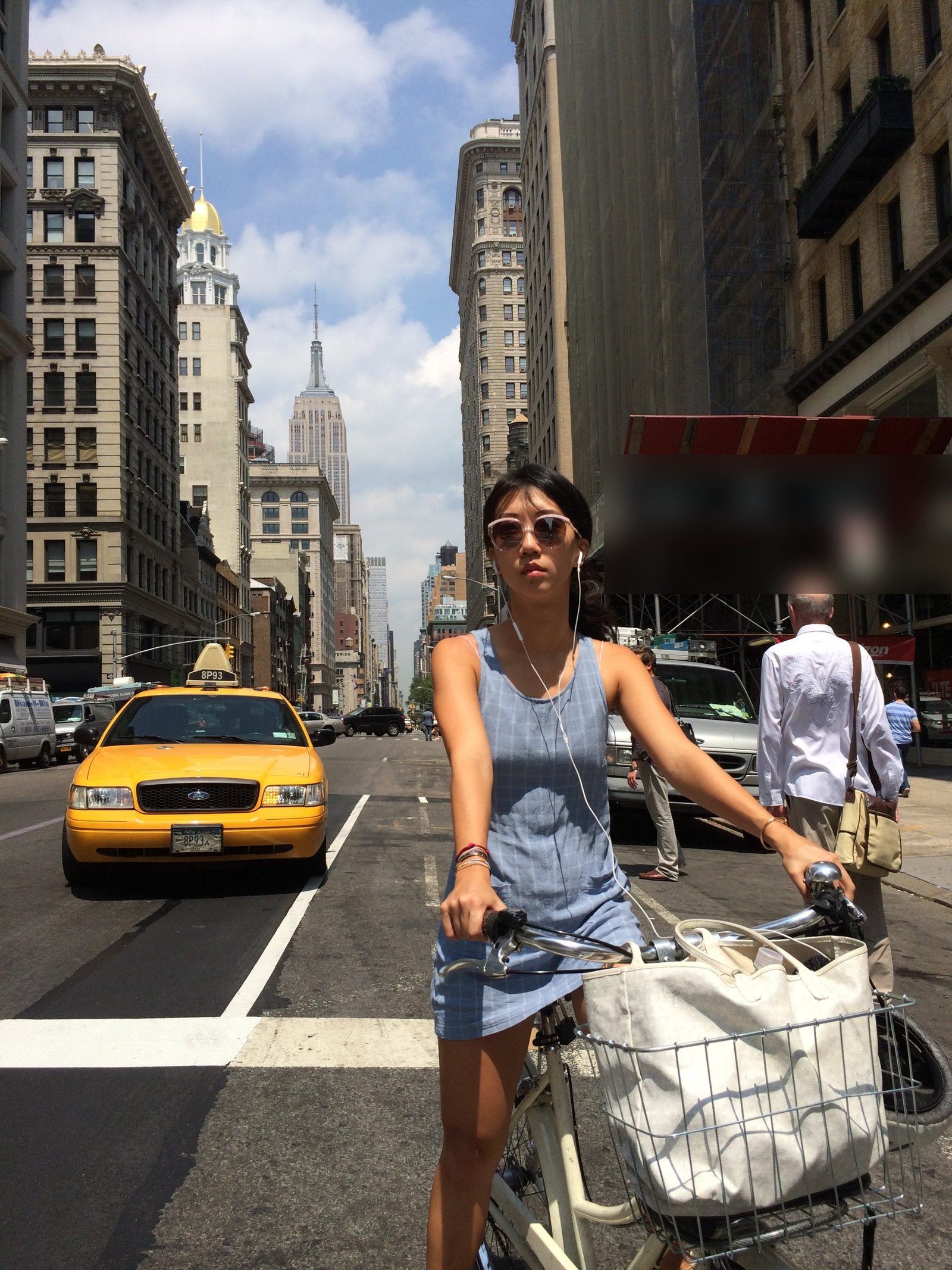 Woman with bicycle in a New York City crosswalk with a yellow cab and the Empire State Building behind her — street photography by Anthony Danielle, Astoria photographer
